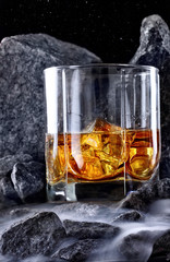 Glass of whiskey and ice.Creative photo glass of whiskey in stone mountain with fog.Copy space.Advertising shot