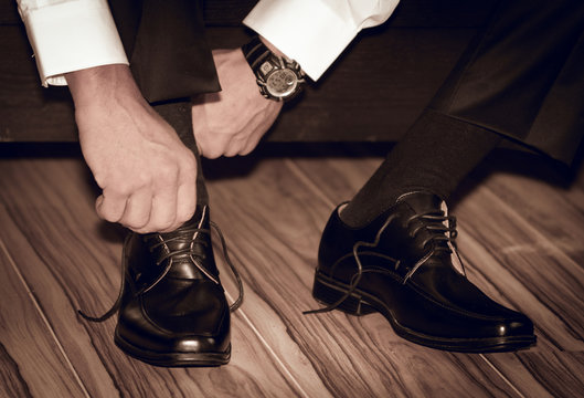 Groom wearing shoes on wedding day tying the laces