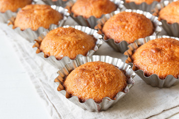 A few muffins in the baking dish. White, wooden background.