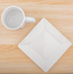 White ceramic plate and mug isolated on wooden background close up