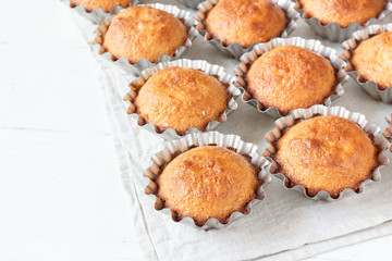 A few muffins in the baking dish. White, wooden background.