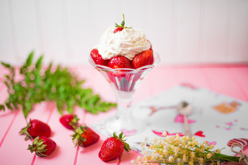 Summer dessert: strawberries and cream on a wooden table