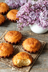 A few muffins on wooden background. A bouquet of lilacs, the broken cupcake.