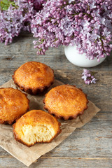 A few muffins on wooden background. A bouquet of lilacs, the broken cupcake.