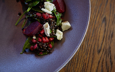 Healthy Beet Salad with fresh sweet baby spinach, kale lettuce, nuts, feta cheese and toast melted. Fresh salad with beets, closeup. Beetroot (beet) chopped for salad in bowl over rustic wooden table.