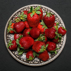 fresh ripe useful fruit strawberry in a clay bowl closeup on a black background