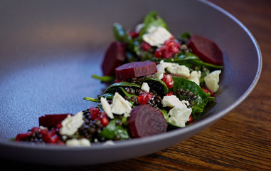 Healthy Beet Salad with fresh sweet baby spinach, kale lettuce, nuts, feta cheese and toast melted. Fresh salad with beets, closeup. Beetroot (beet) chopped for salad in bowl over rustic wooden table.