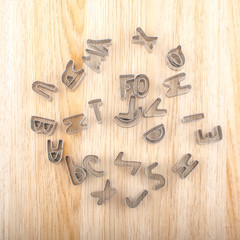 Biscuit cake mold cutter letters alphabet isolated on wooden background close up
