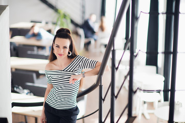 Happy young business woman standing in a cafe and smiling while looking at the camera.