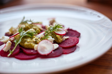 Healthy Beet Salad with fresh sweet baby spinach, kale lettuce, nuts, feta cheese and toast melted. Fresh salad with beets, closeup. Beetroot (beet) chopped for salad in bowl over rustic wooden table.