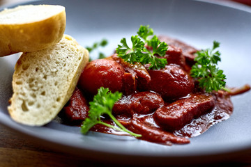 warm salad with chicken liver and grapes on the white plate. Warm salad from turkey liver. Warm salad with chicken liver in raspberry sauce.