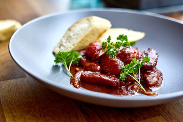 warm salad with chicken liver and grapes on the white plate. Warm salad from turkey liver. Warm salad with chicken liver in raspberry sauce.