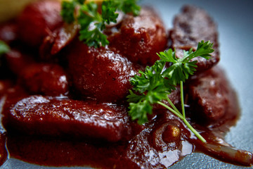 warm salad with chicken liver and grapes on the white plate. Warm salad from turkey liver. Warm salad with chicken liver in raspberry sauce.