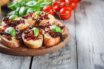 Appetizer bruschetta with sun-dried tomatoes, olives and mozarella.