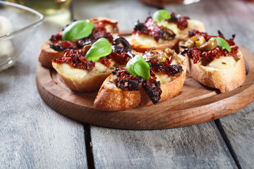Appetizer bruschetta with sun-dried tomatoes, olives and mozarella.