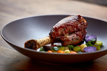 Roasted pork knuckle in a frying pan with potato and salad, top view. Lamb Knuckles with Vegetable in Red Wine Sauce.