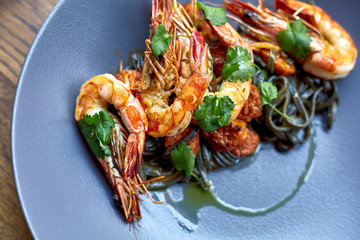 Cooked shrimps,prawns with seasonings on stone background. Fried shrimp with rosemary in a portioned frying pan on a dark table top view.  