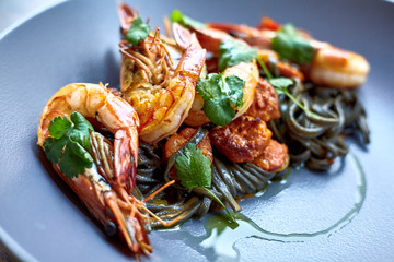 Cooked shrimps,prawns with seasonings on stone background. Fried shrimp with rosemary in a portioned frying pan on a dark table top view.  