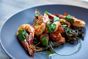 Cooked shrimps,prawns with seasonings on stone background. Fried shrimp with rosemary in a portioned frying pan on a dark table top view.  