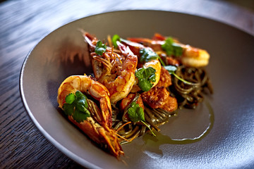 Cooked shrimps,prawns with seasonings on stone background. Fried shrimp with rosemary in a portioned frying pan on a dark table top view.  