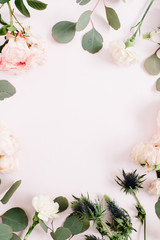 Round frame wreath made of rose flowers, eringium flower, eucalyptus branches on pale pastel pink background. Flat lay, top view. Floral background