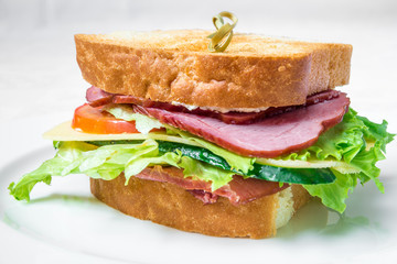 Delicious fast food. Sandwich with bacon, cucumber, cheese and herbs. Horizontal frame