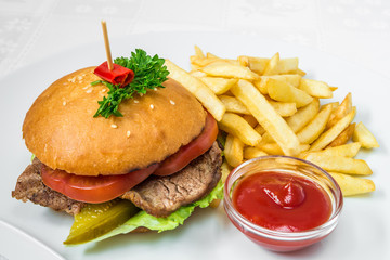 Delicious fast food. Burger with meat, cucumber and herbs, French fries and sauce. Horizontal frame