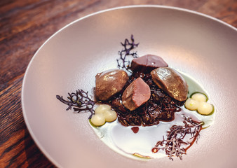 warm salad with chicken liver and grapes on the white plate. Warm salad from turkey liver. Warm salad with chicken liver in raspberry sauce.