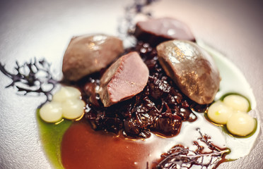warm salad with chicken liver and grapes on the white plate. Warm salad from turkey liver. Warm salad with chicken liver in raspberry sauce.