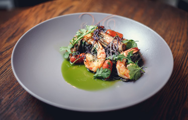 Cooked shrimps,prawns with seasonings on stone background. Fried shrimp with rosemary in a portioned frying pan on a dark table top view. 