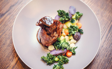 Roasted pork knuckle in a frying pan with potato and salad, top view. Lamb Knuckles with Vegetable in Red Wine Sauce.