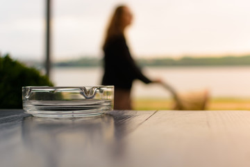 Ashtray on the table. In the background mother with a stroller in a blur