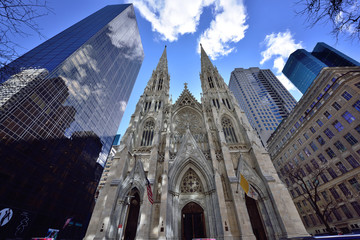 St. Patrick's Cathedral; frontal image in earl morning of St. Patrick's Cathedral with reflected light on spires and clouds over towers; contrast to new buildings - obrazy, fototapety, plakaty