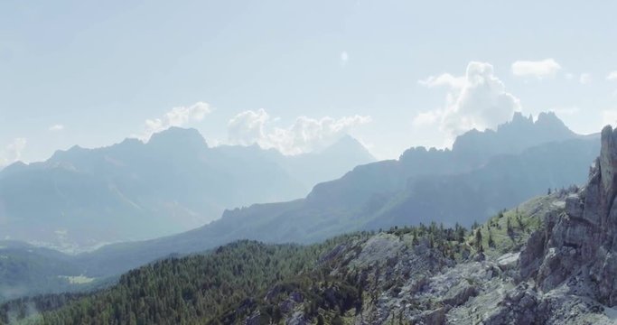 Aerial flight above mountain top with pines and rocks in sunny day. Summer adventure journey in mountain nature outdoors. Travel exploring Alps, Dolomites,Cinque Torri, Italy. 4k drone side video