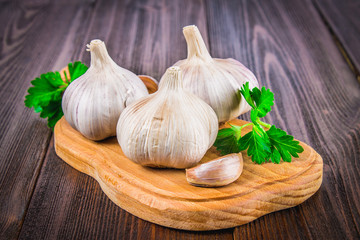 Top view, flat lay. Garlic clove and garlic bulb on a brown wooden table.