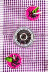 Smoothies of black currant in glass glasses with straws on a white wooden table. Top view.