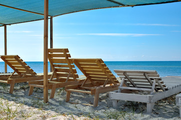 Wooden sunbeds on the background of blue sea. Resorts, vacation and seascapes.