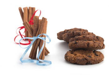 Biscuits with chocolate, festive cinnamon sticks on white background
