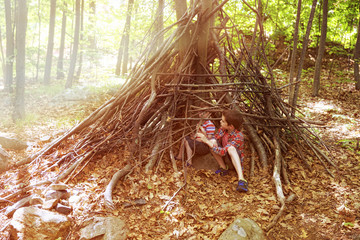 Children play in a hut out of twigs. wooden stick hut house  in the forest