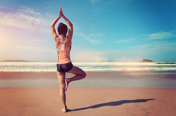 Young fitness woman wear swimsuit practice yoga on the beach