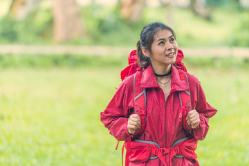 Asian lady backpacker with red jacket stand and enjoying in a summer nature park