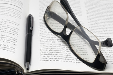 Glasses and pen on the open book,thai language book