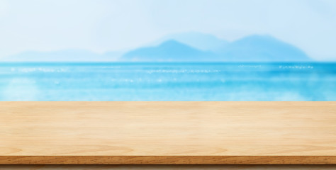 Empty brown wood table top with blur navy blue ocean bokeh light,Mock up for display or montage of product,Banner or header for advertise on social media,Summer background