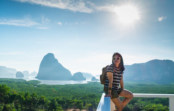 Happy young traveler woman backpacker sitting at mountain panorama view point and sea  and  enjoying a beautiful of nature at ,Freedom wanderlust,Khao Samed Nang Chee Viewpoint,Phang Nga,Thailand.
