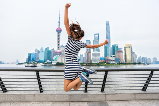 Happiness in city. Happy woman jumping of success in front of urban skyline in Shanghai, China. Winning people concept.