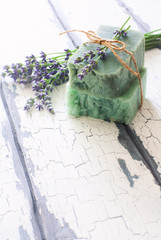 Bars of handmade soap with lavender flowers over white wood grunge background.