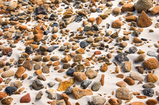 smooth round pebble stones on the sand beach backgound