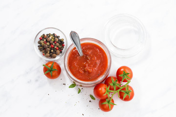 tomato sauce in a glass jar and white background, top view