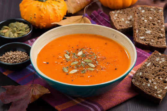pumpkin soup in a bowl on wooden table, closeup