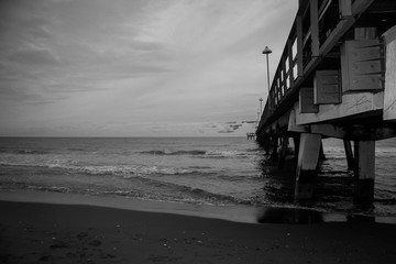 Pier along with the beach with dark cloudy sky in black and white style